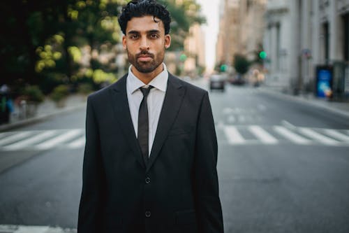 A Man in Black Suit Standing on the Street