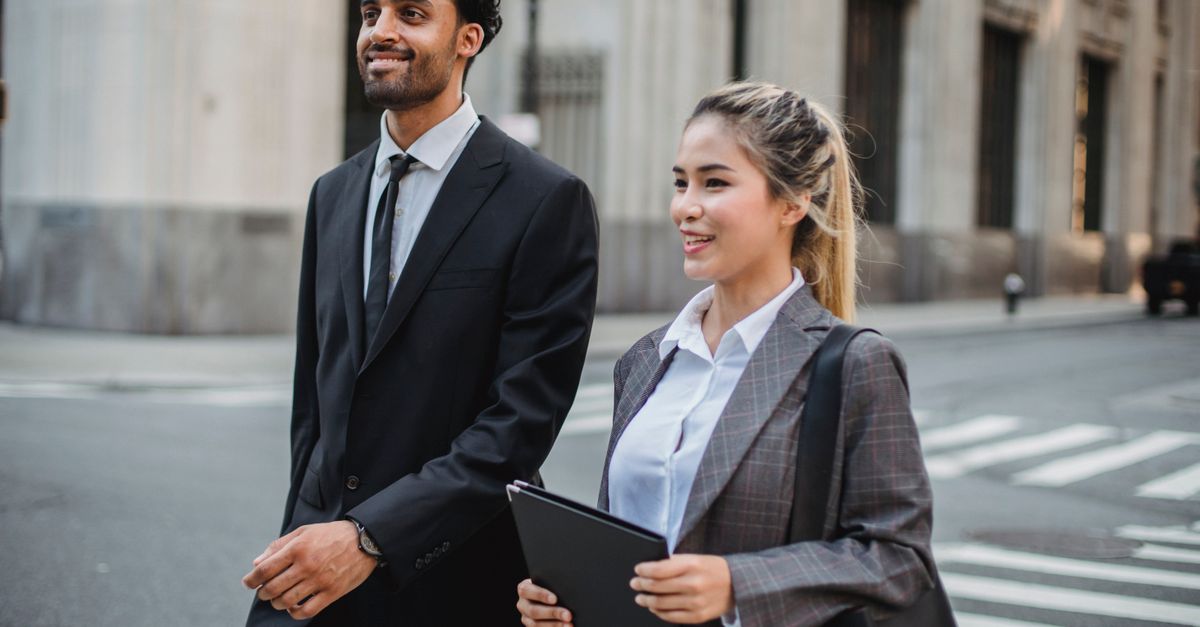 Business professionals in corporate attire walking confidently in an urban street setting.