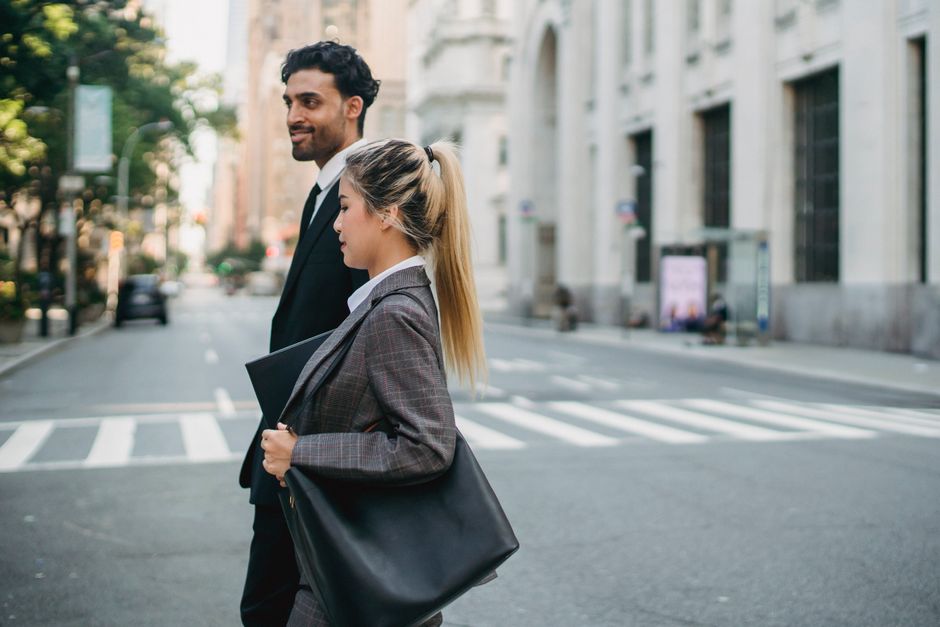 Profesionales de negocios caminando con confianza por una calle de la ciudad, mostrando trabajo en equipo y un estilo de vida moderno.