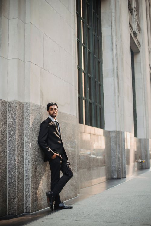 Free A confident businessman in a full suit poses against a city building, exuding elegance and style. Stock Photo