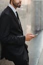Businessman Leaning Against Wall Using Phone