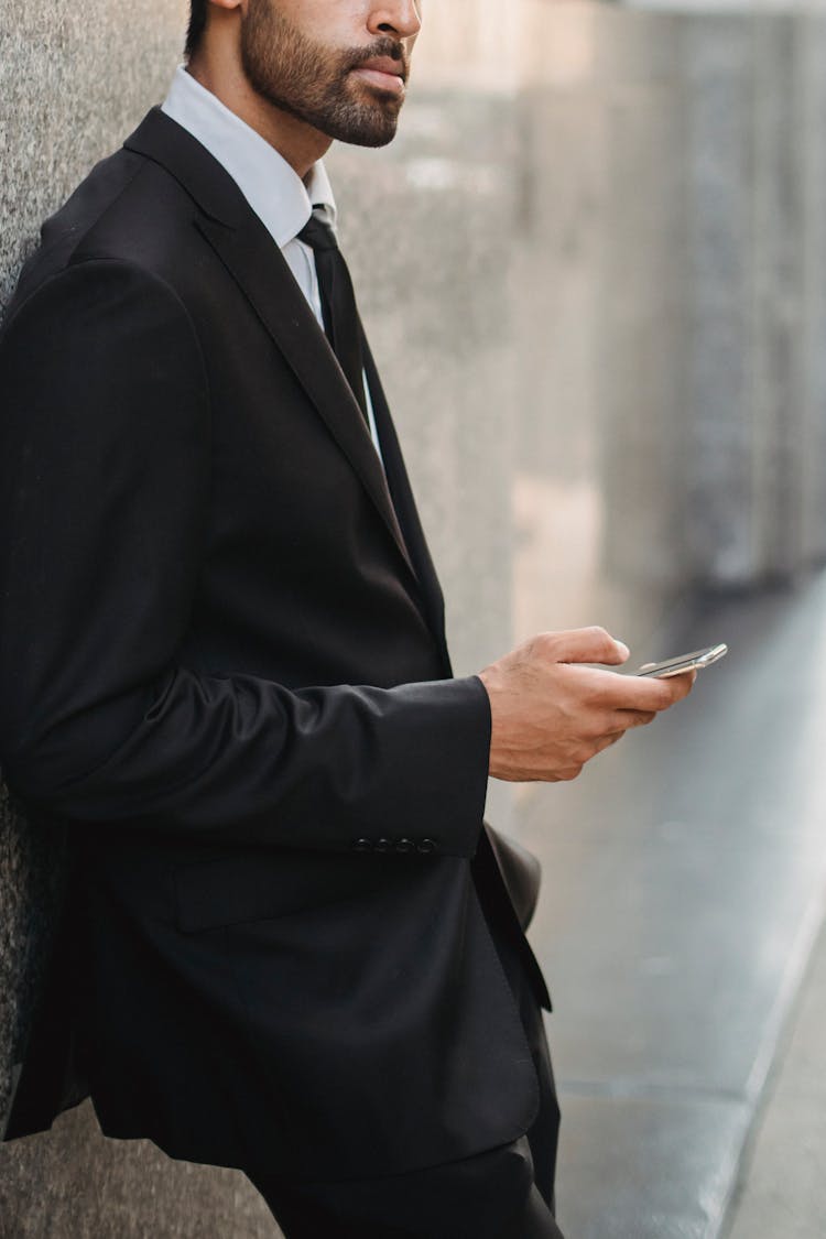 Businessman Leaning Against Wall Using Phone