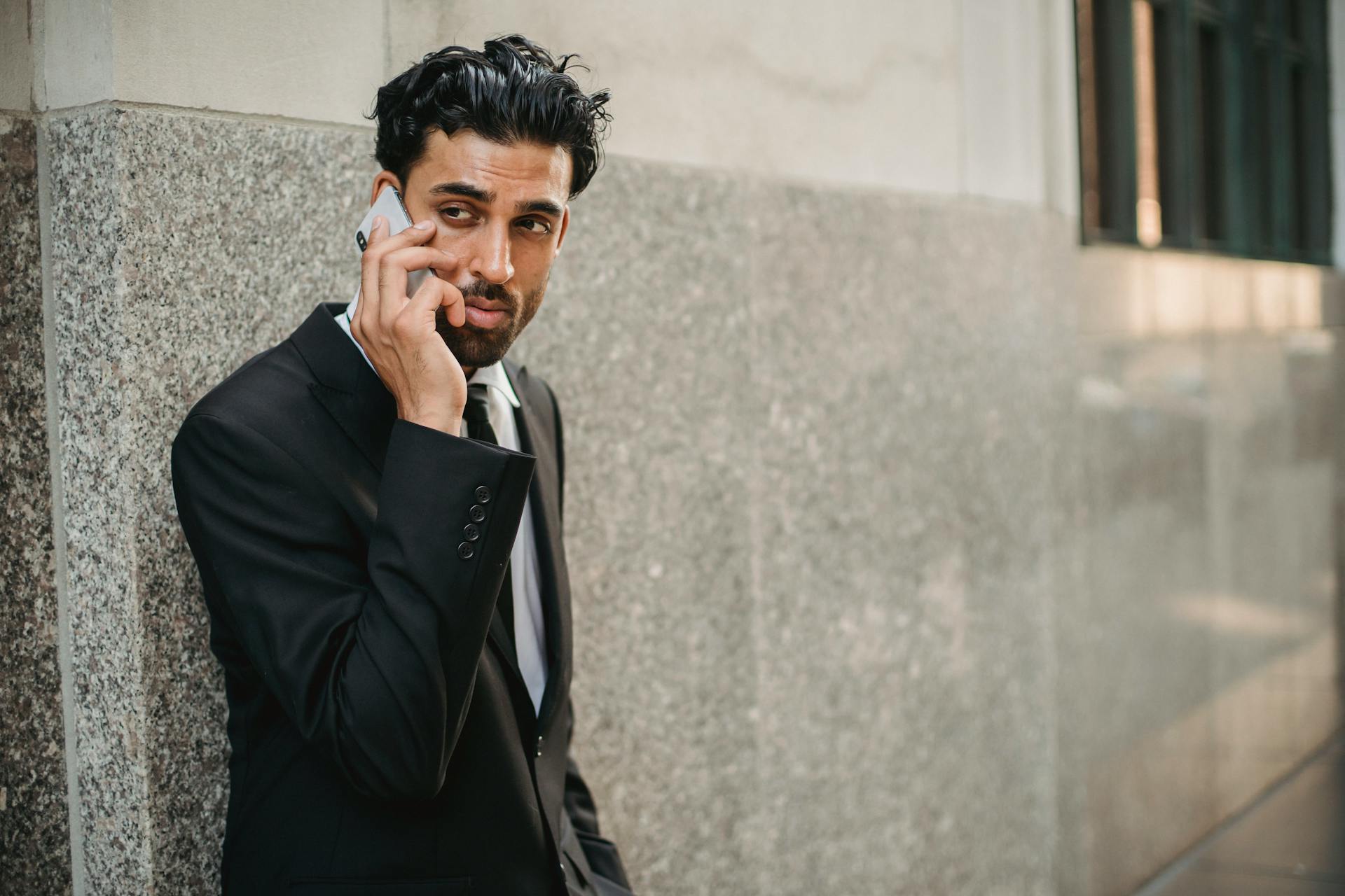 Businessman in a suit talking on a phone outdoors, portrait of a confident businessman.