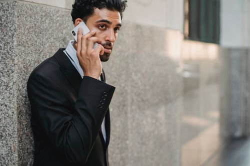 Free Professional businessman in a suit having a phone conversation outside office building. Stock Photo
