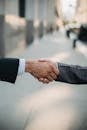 两位商人在户外握手，象征着城市环境中的合作与协议