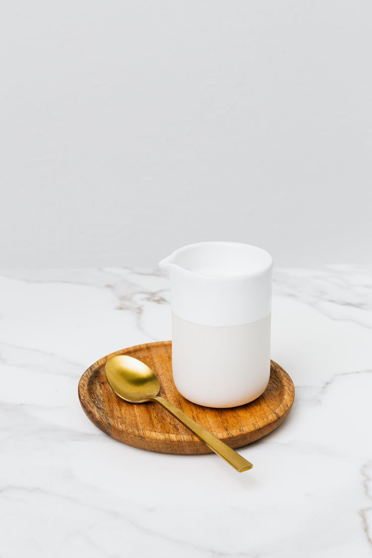 White Ceramic Milk Server On The Wooden Saucer