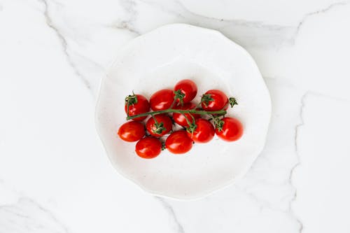Free Overhead Shot of Red Cherry Tomatoes on a White Ceramic Plate Stock Photo
