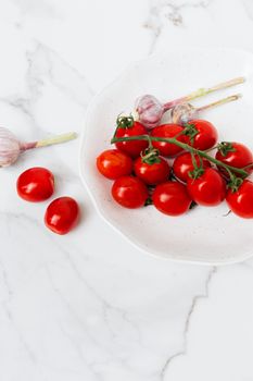 白色盘子上摆满了充满活力的樱桃西红柿和大蒜，非常适合美食博客