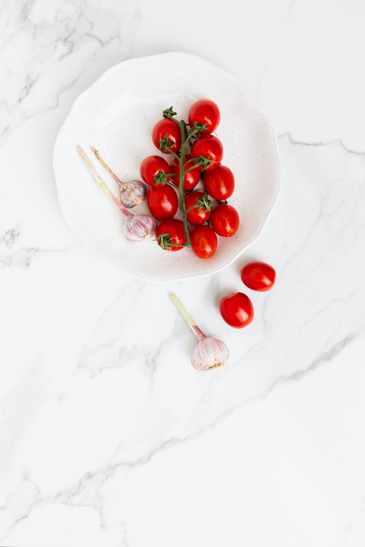 Tomatoes And Garlic On The White Plate