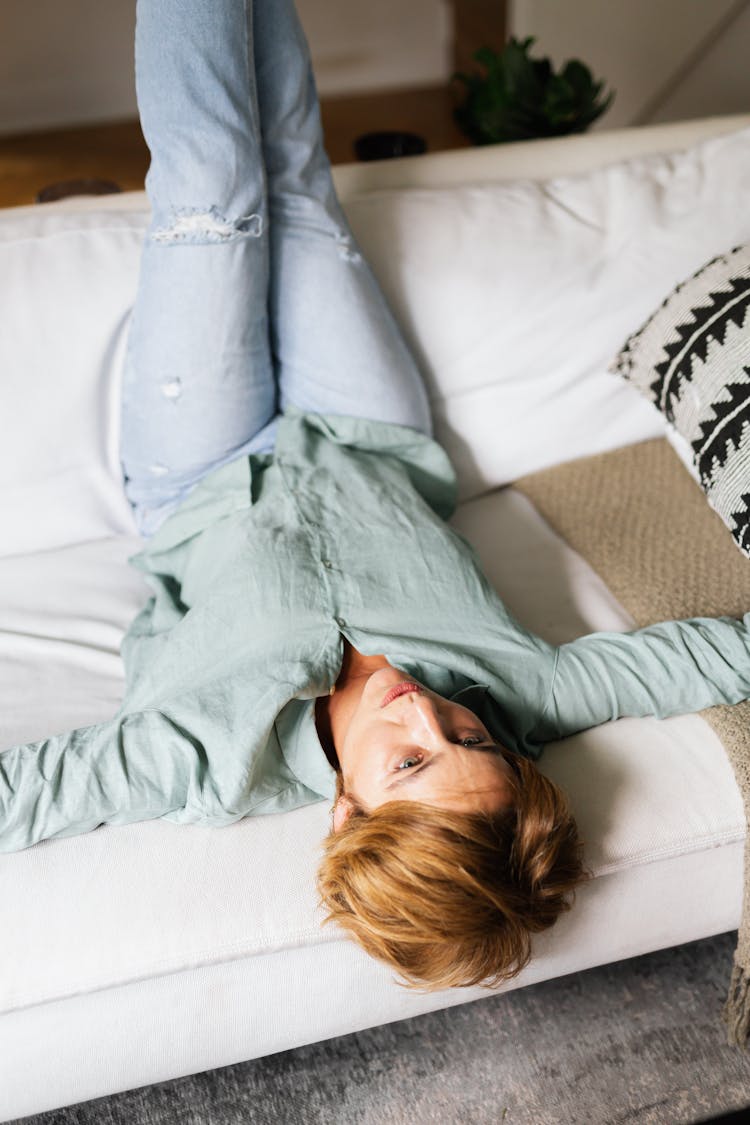 A Woman Lying On The Couch With Her Feet Up