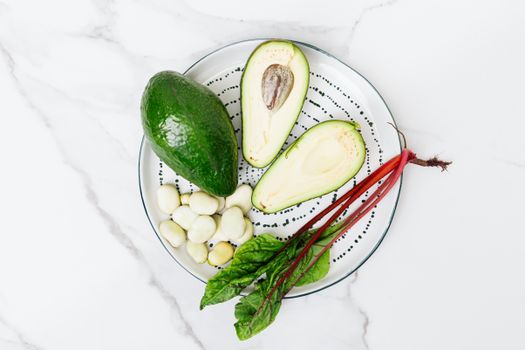 Top view of fresh avocado, beetroot, and broad beans on a plate, perfect for healthy food concepts.