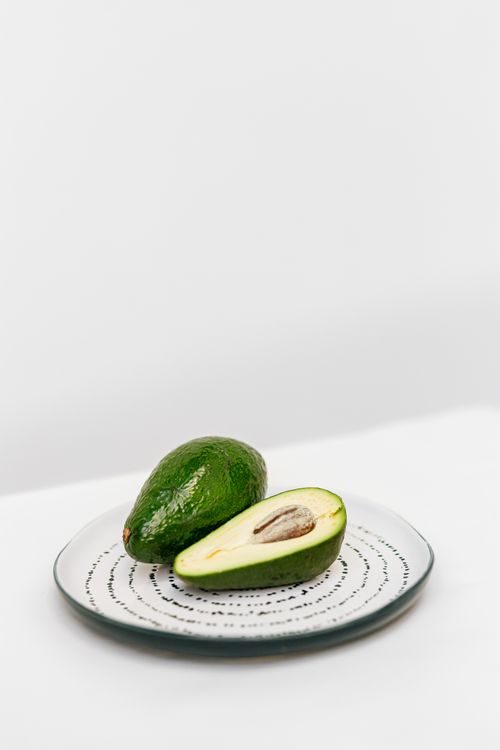 Free A ripe avocado, half sliced, on a detailed ceramic plate, showcasing its vibrant green and creamy texture. Stock Photo