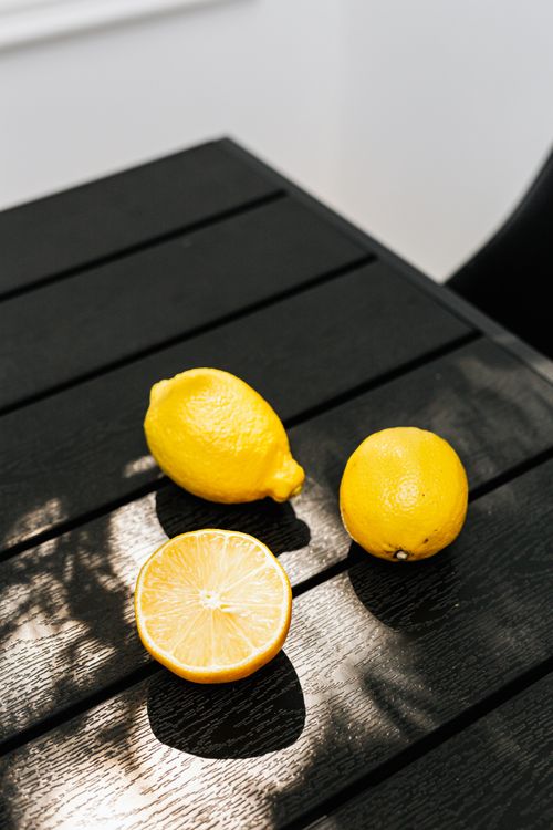 Free Sliced and whole lemons on a dark wooden table with soft lighting. Stock Photo