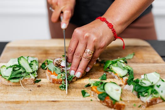 Close-up of hands slicing vegetable sandwiches on a wooden board.