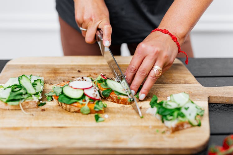 Photo Of A Person Slicing A Sandwich With Vegetables