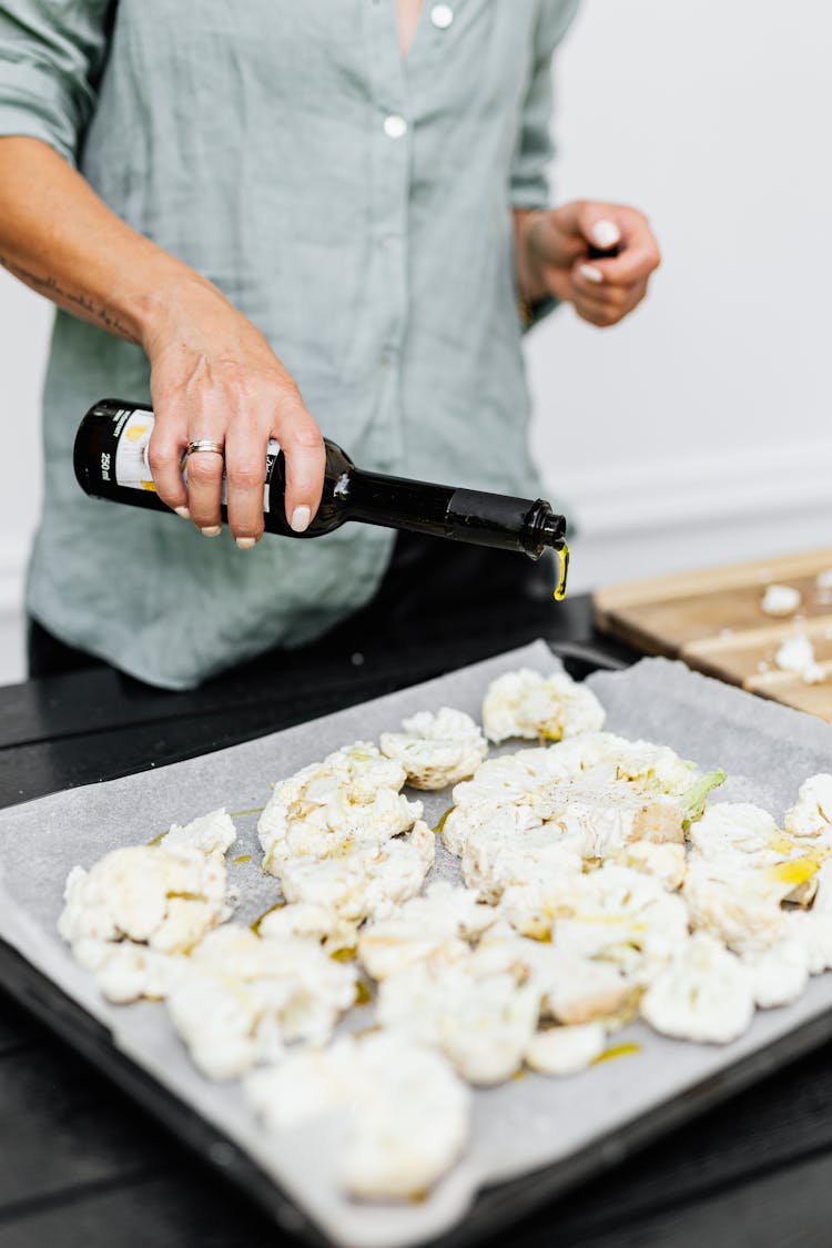 Woman Pouring Oil Over Food On A Baking Tray