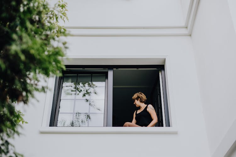 Woman Standing In Open Window