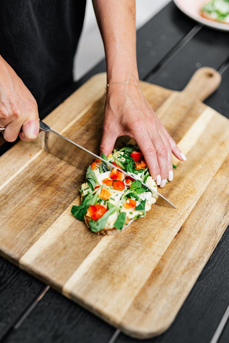 Close-up Of Woman Cutting Food On Board