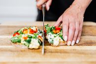 Person Holding Stainless Steel Fork and Knife Slicing Vegetable