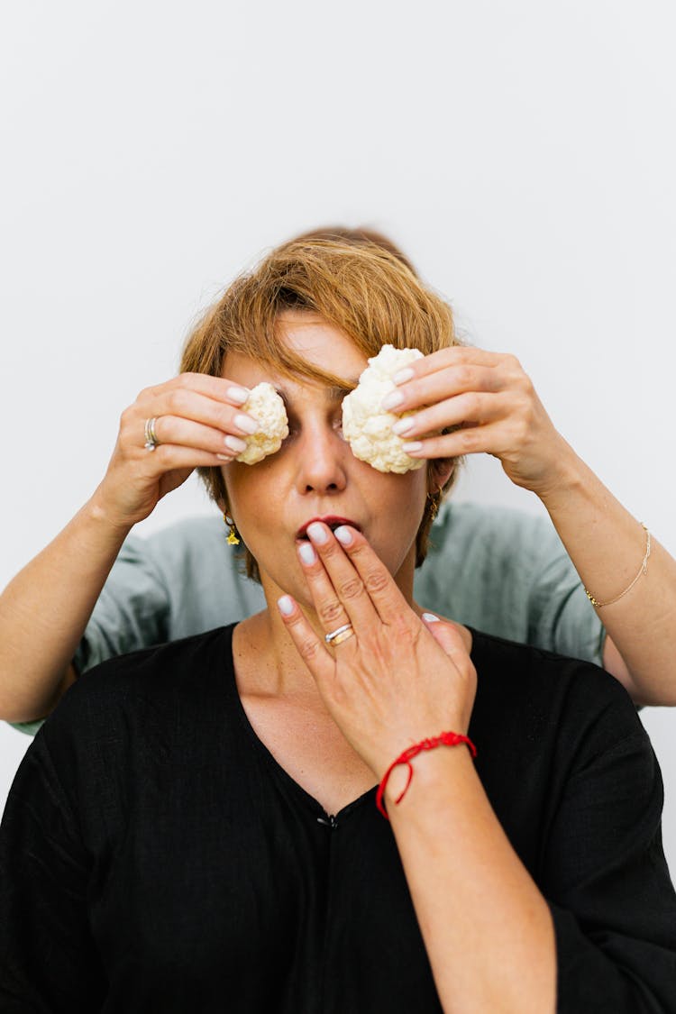 Hands Covering Woman Eyes With Vegetables