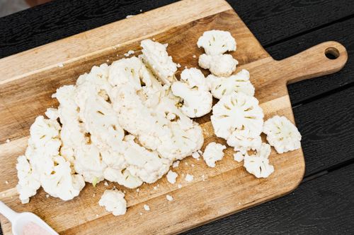 Free Top view of fresh sliced cauliflower on a wooden chopping board, ready for cooking. Stock Photo