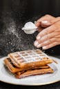 Person Holding a Waffle With White Cream