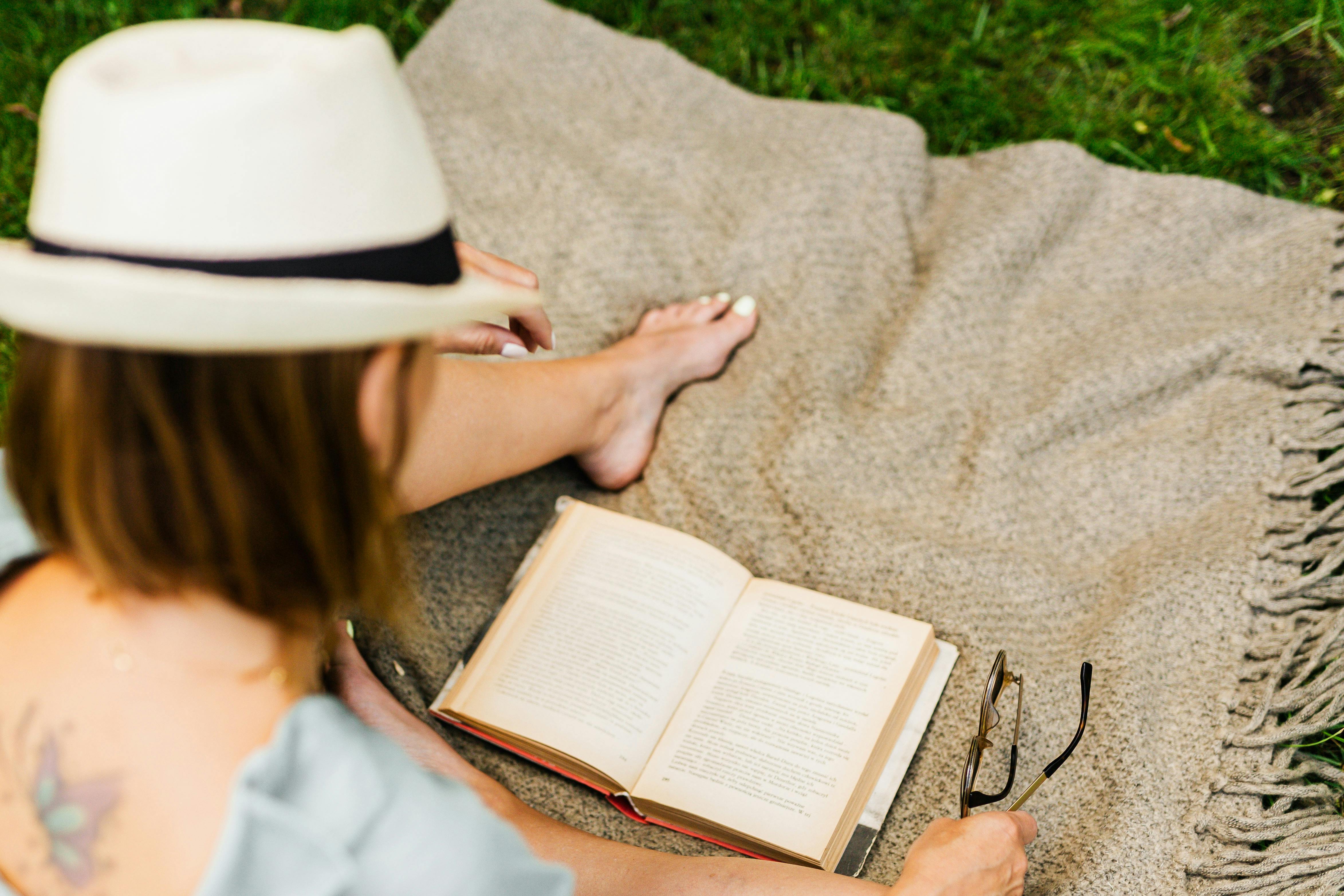 woman reading book outdoors as an offline alternative to digital minimalism screen time