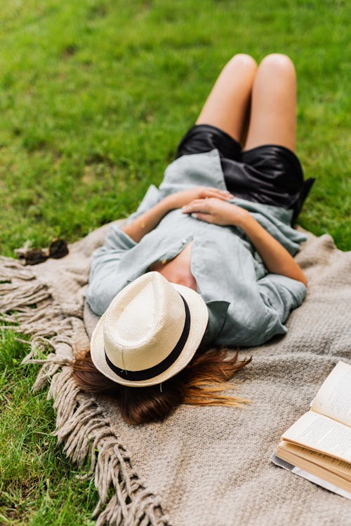 Free Woman Lying on Grass with Hat on Face  Stock Photo