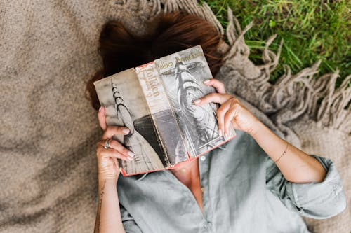 Woman Lying on Blanket Reading Book