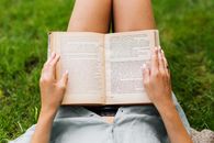Person Reading Book on Green Grass Field