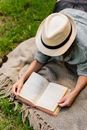 Woman Lying on a Blanket Outdoors and Reading a Book
