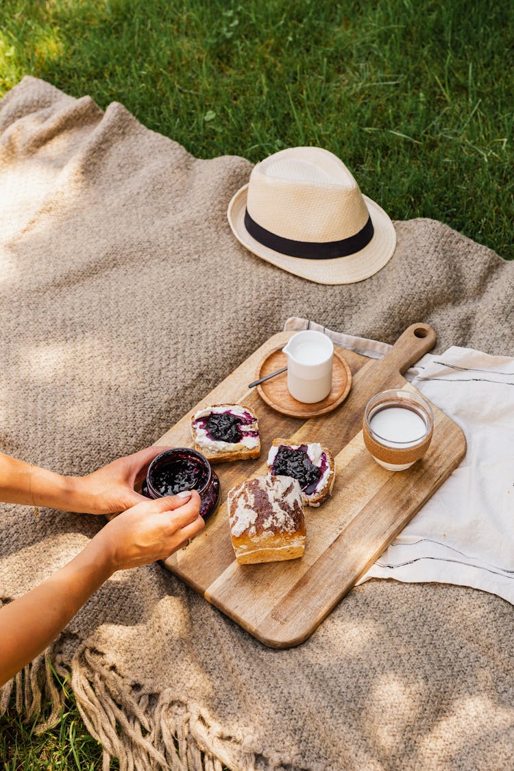 Unrecognizable Woman Preparing Picnic Breakfast On Grass