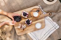 Person Holding Brown Wooden Chopping Board With Sliced of Bread