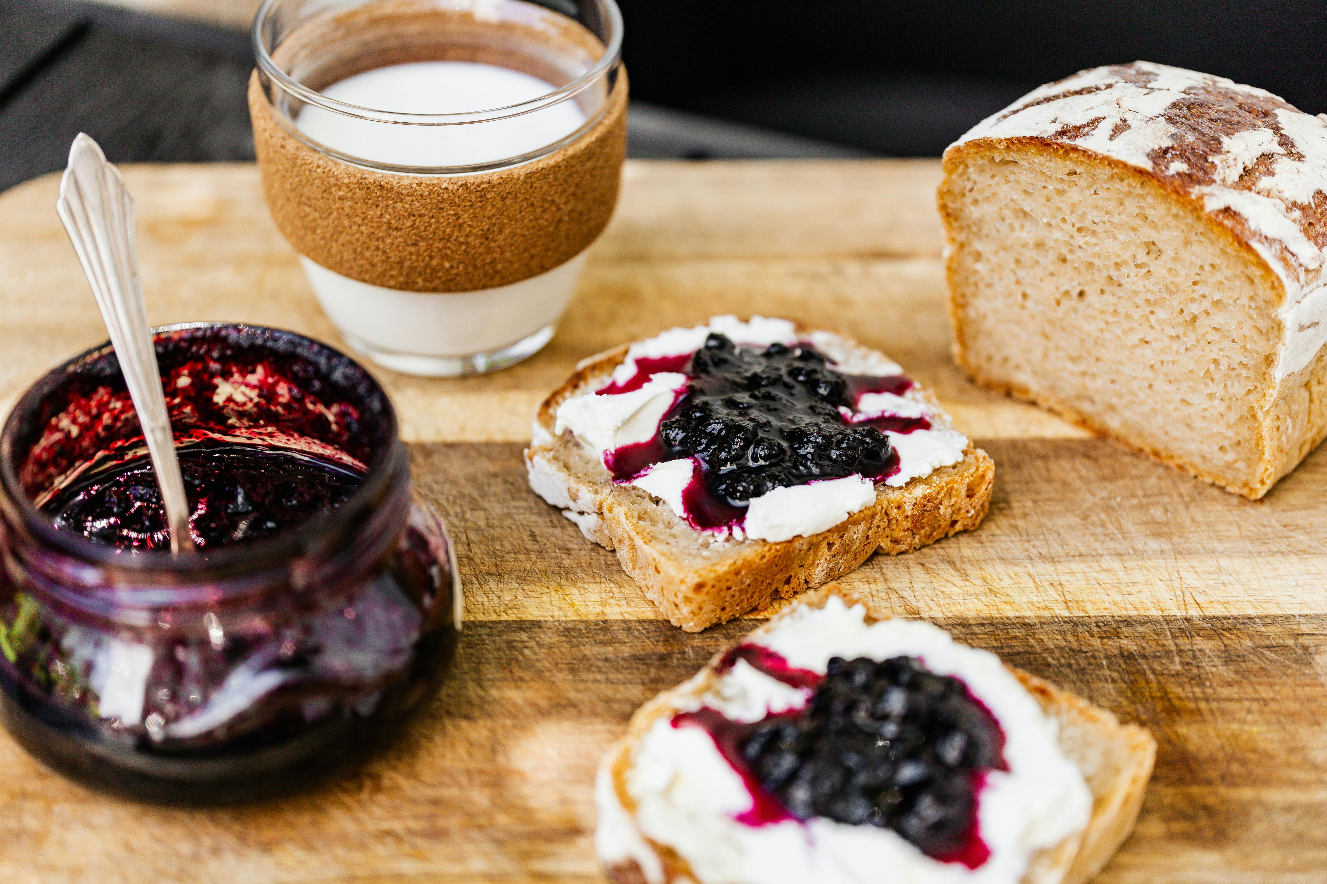 brown bread with jam and white cream on brown wooden table