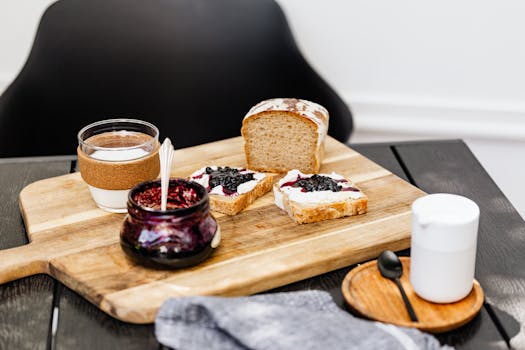 Appetizing breakfast setup with bread, jam, and milk on a rustic wooden board, offering a cozy morning vibe.