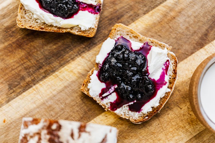 Bread With Blueberry Jam And Cream On Brown Wooden Table