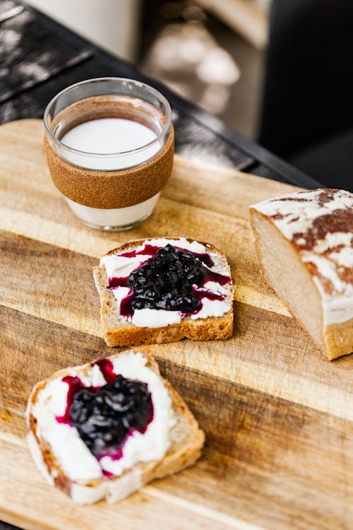 Free Bread With Blueberry Jam and White Cream on Brown Wooden Chopping Board Stock Photo