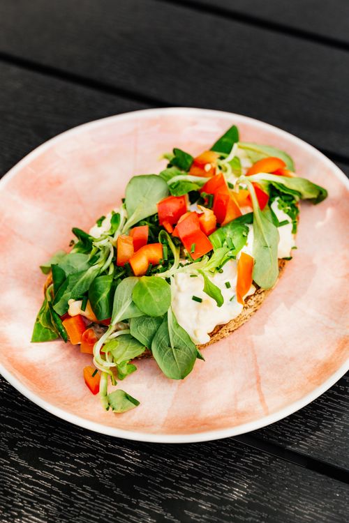 Free A delicious open sandwich with fresh vegetables and creamy cheese on a pink plate, perfect for a light meal. Stock Photo