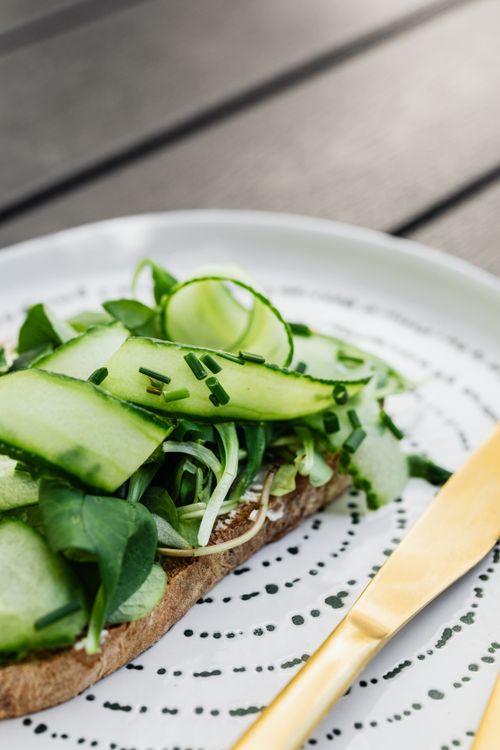 Free Close-up of a fresh cucumber sandwich with green leaves and chives on a decorative plate. Stock Photo