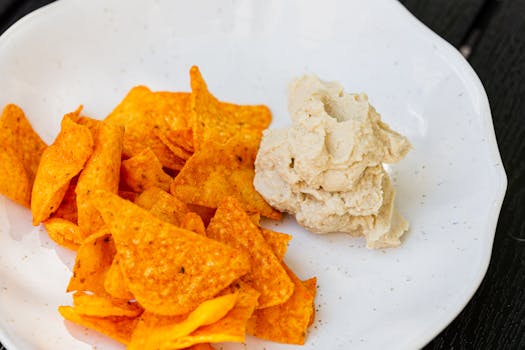 A close-up shot of spicy nachos served with creamy hummus dip, perfect for snacking.