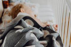 A baby sleeps peacefully in a crib with a cozy blanket and a teddy bear nearby.
