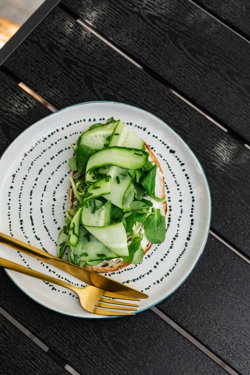 Free Vegetable sandwich with fresh cucumber and spinach on a plate with gold cutlery. Stock Photo