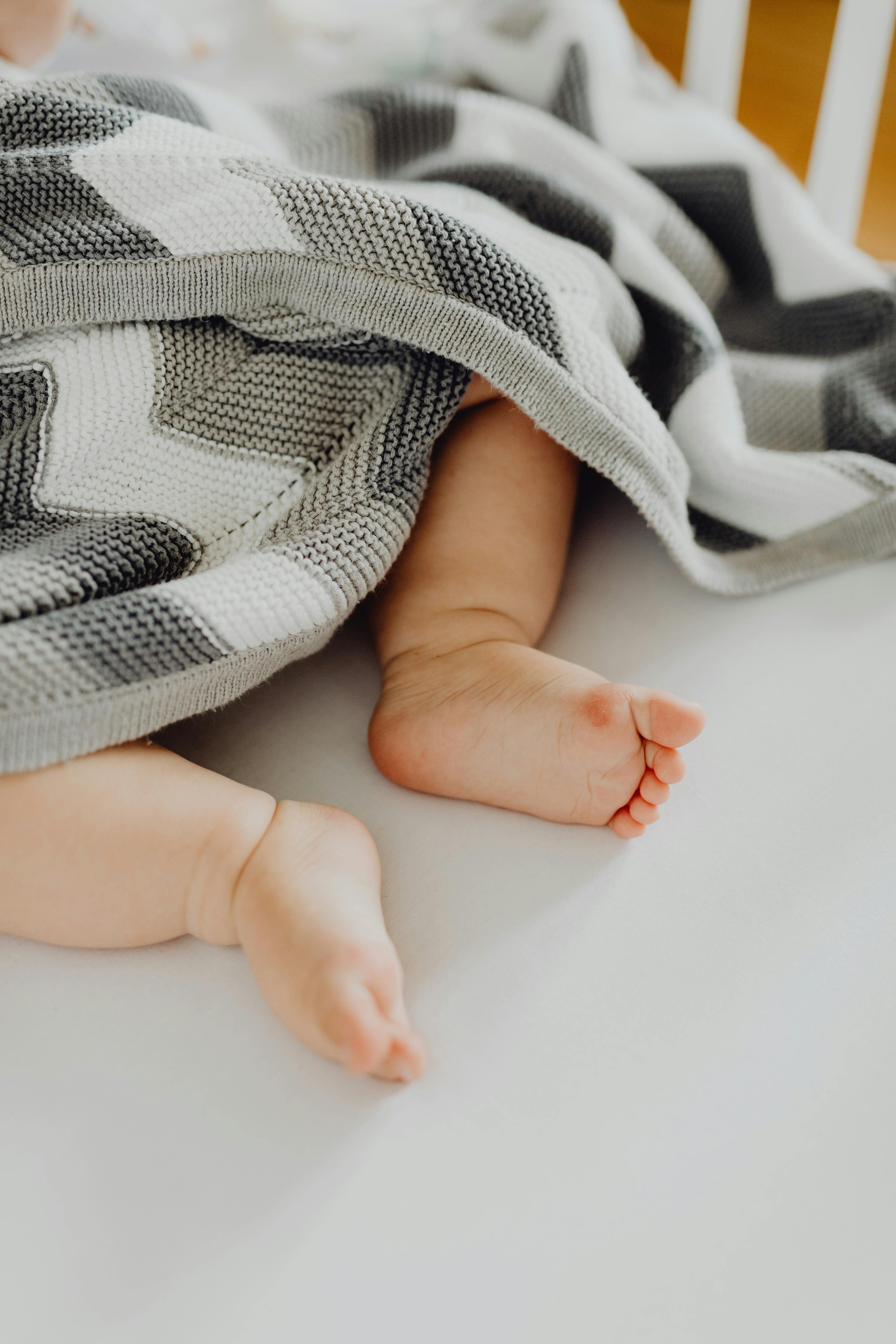 close up photo of baby s little feet under a blanket