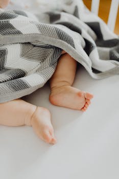 从图案毯子下探出的可爱婴儿脚，象征着温暖与纯真