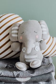 这只可爱的毛绒大象玩具配有条纹垫子，营造出舒适的环境