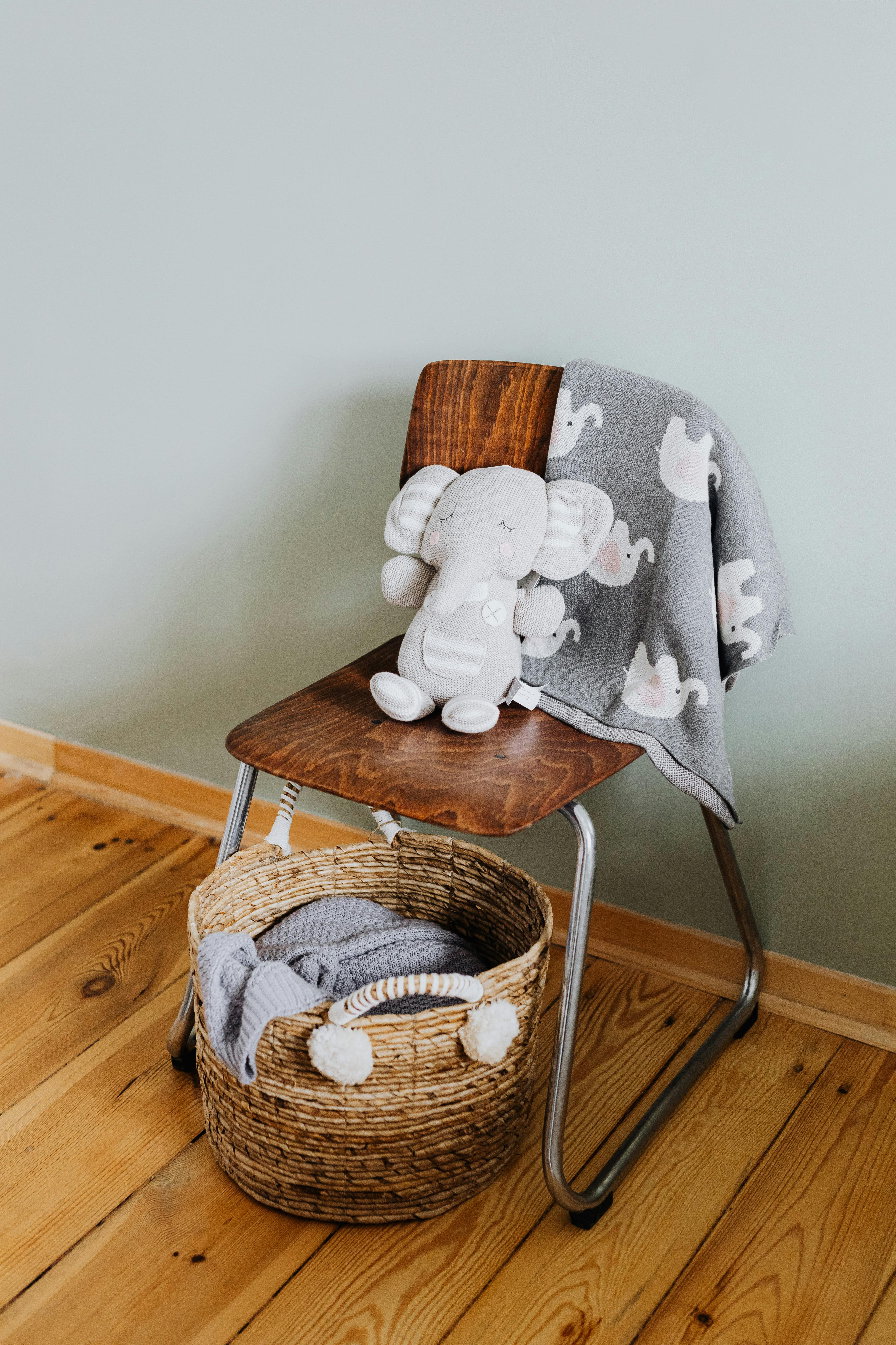 Wooden chair with elephant toy and blanket in baby room setting.