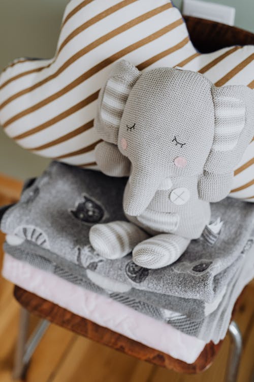 Close-up Photo of an Elephant Plush Toy on Top of Folded Blankets 