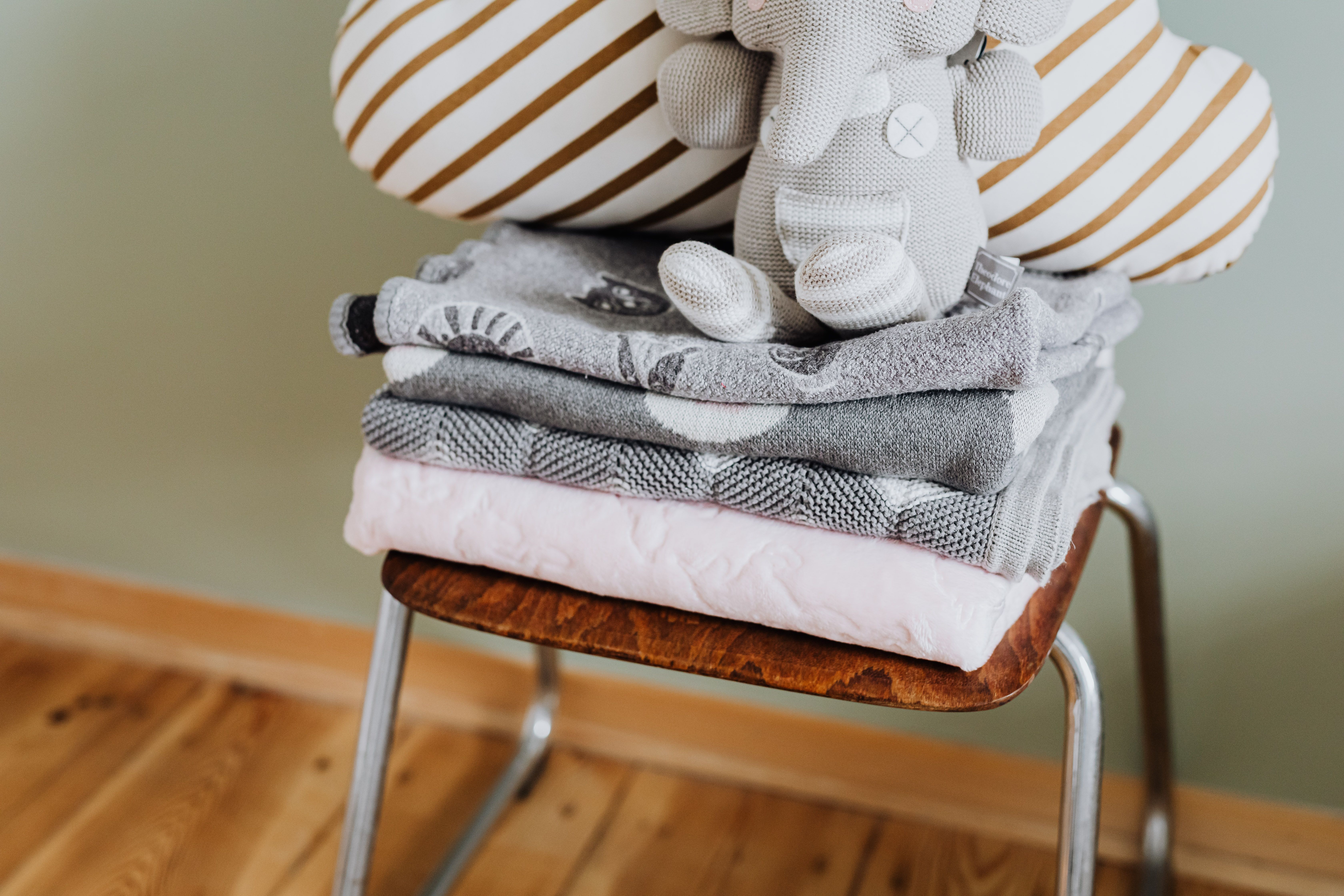 Stack of folded blankets representing the buy it for life blanket constructions ranked by the specific failure mode of each material.