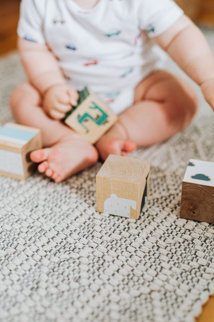 Baby Sitting On Carpet Playing With Toy Blocks
