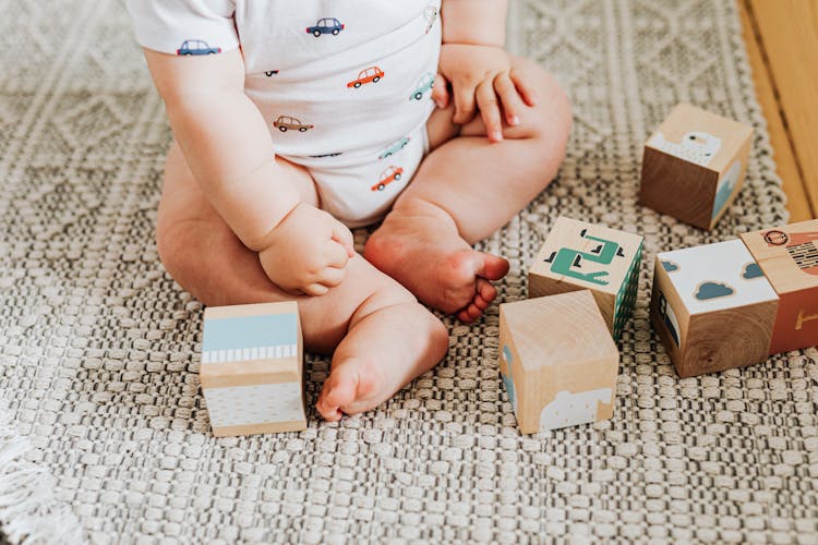 Baby Sitting On Carpet Among Toy Blocks